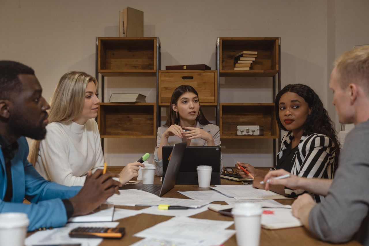 A multicultural group of professionals discussing strategies in a modern office setting.