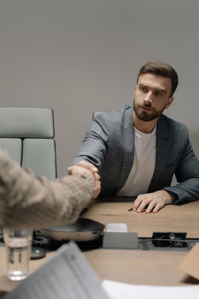About Two businessmen in a modern office shaking hands across a table. Professional setting.